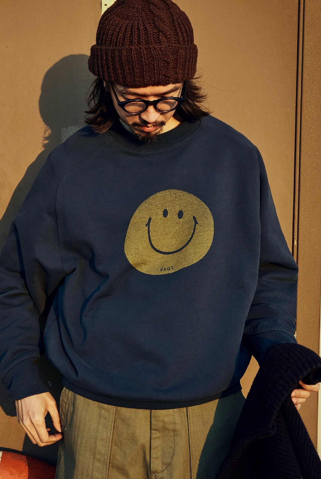 USAGE Washed Cotton Raglan Smiley Sweatshirt in Blue - On Male Model