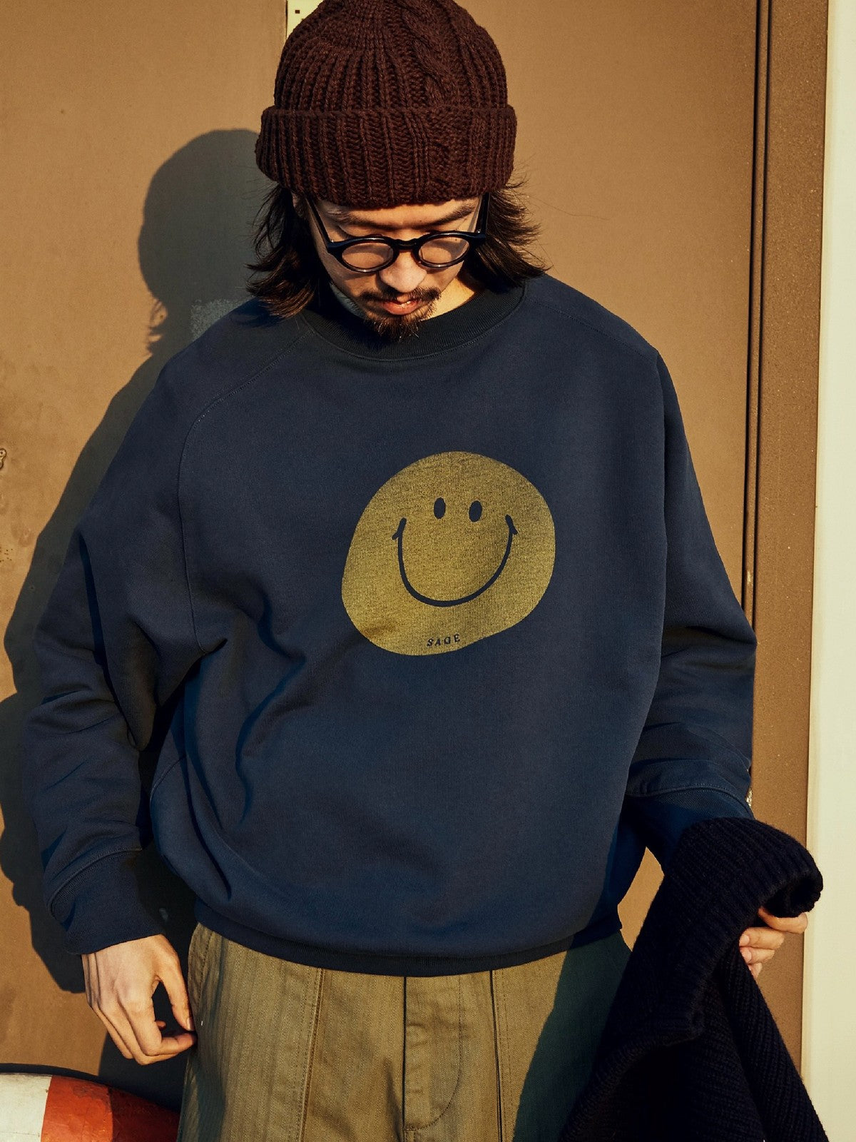 USAGE Washed Cotton Raglan Smiley Sweatshirt in Blue - On Male Model