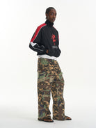 BLINDNOPLAN Paneled Camo Flared Cargo Pants in Green - On Male Model