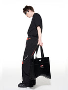 BLINDNOPLAN Textured Faux Leather Asymmetric Tote in Black - On Male Model