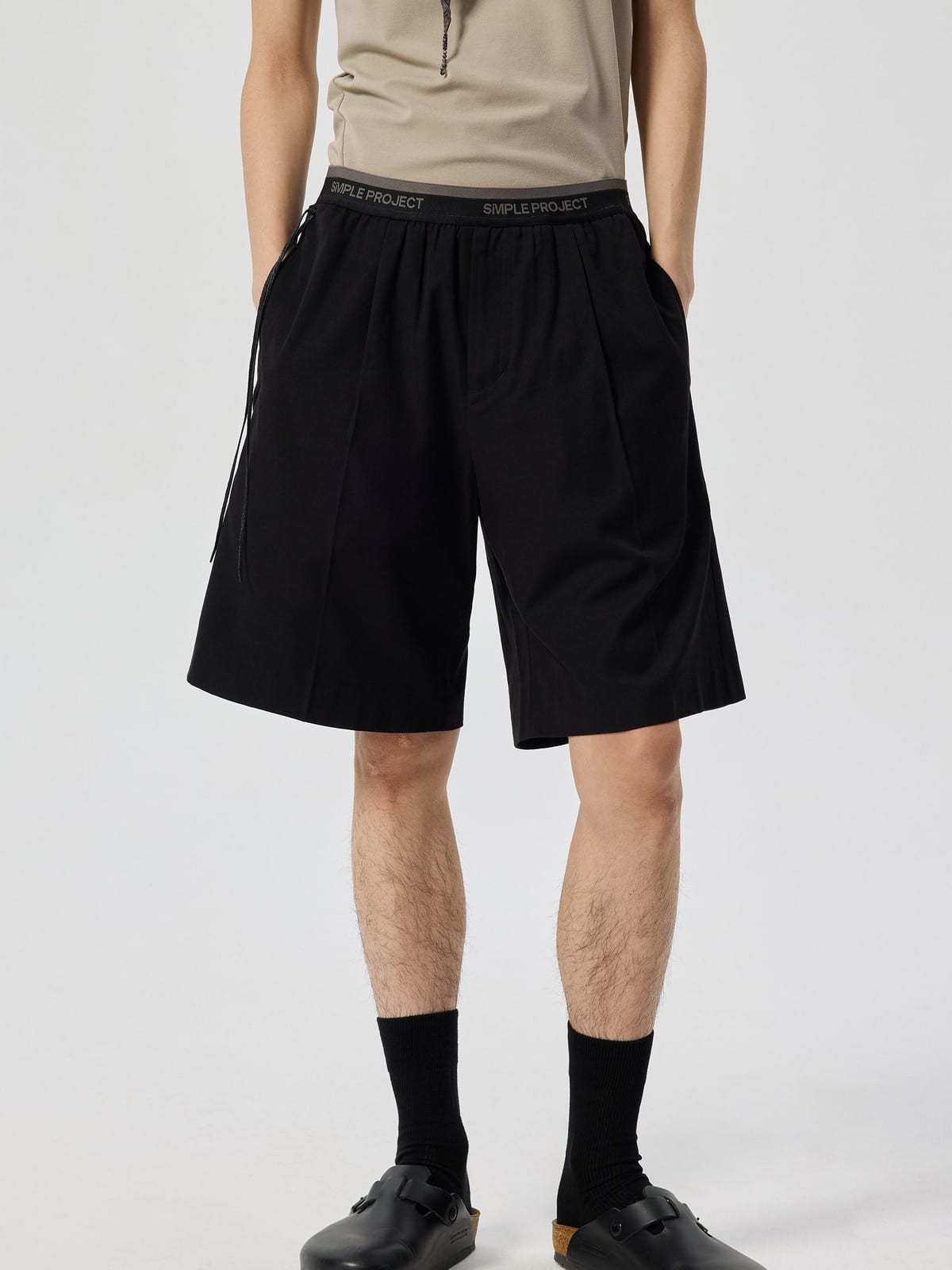 SIMPLE PROJECT Logo Tape Wool Blend Shorts in Black - On Male Model