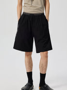 SIMPLE PROJECT Logo Tape Wool Blend Shorts in Black - On Male Model