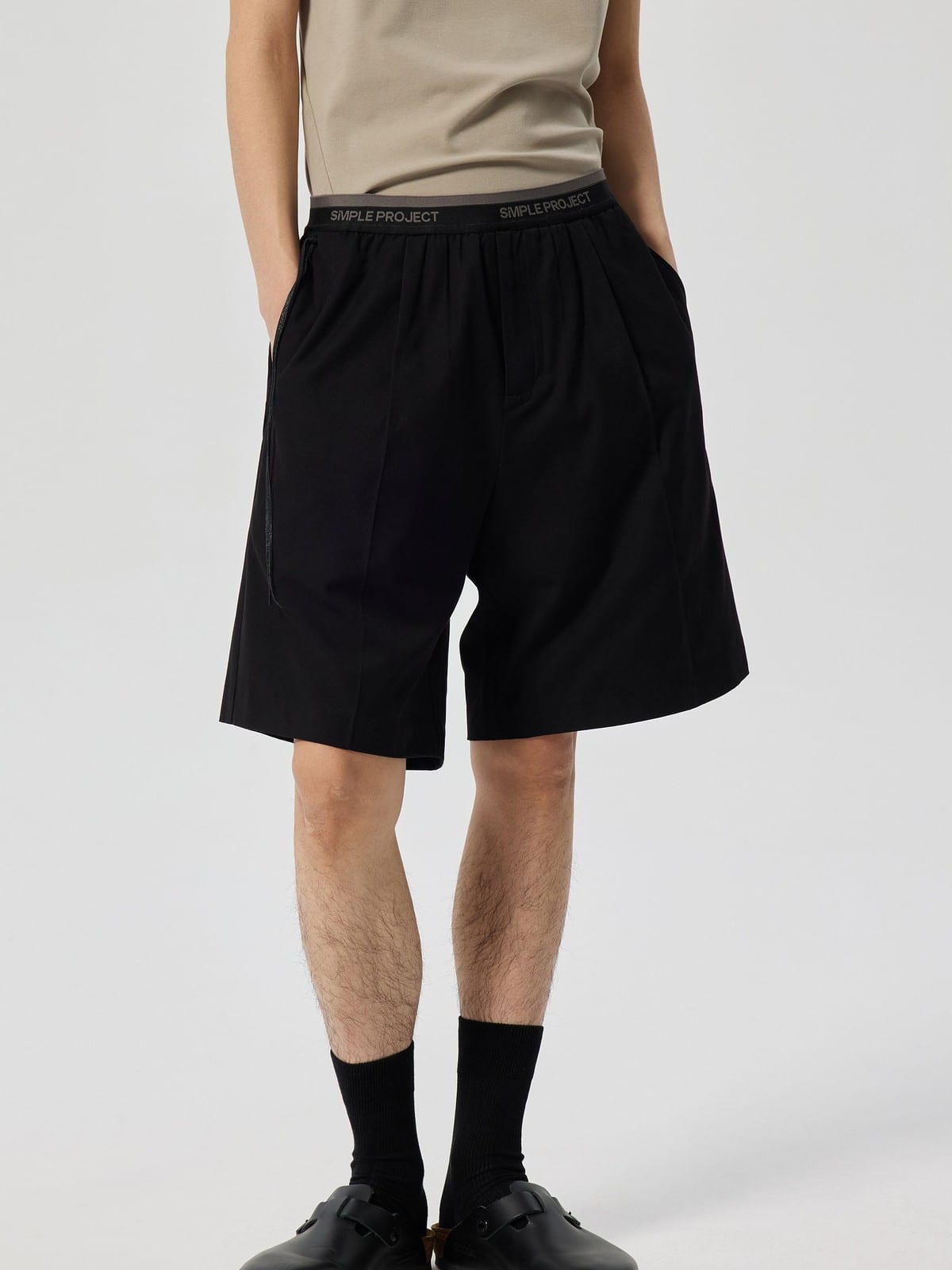 SIMPLE PROJECT Logo Tape Wool Blend Shorts in Black - On Male Model